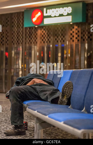 An unidentified homeless man sleeping overnight at Gatwick Airport. Stock Photo