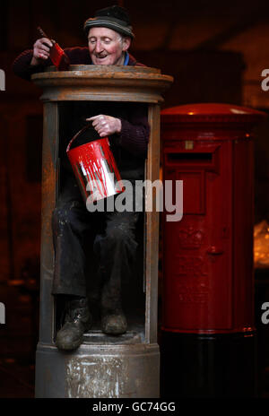 John Cooper, 69, who has been making post boxes since he was 15 years old, starts to paint a Royal Mail pillar box at Machan Engineering in Denny. Machans are the only company in the UK to manufacture the post box for the Royal Mail. Stock Photo