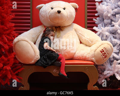 Demi Lindsay, 4, from Bridgeton in Glasgow hugs a giant teddy bear at the opening of the world famous toy retailer Hamleys new 30,000 square foot flagship store located in the new look Glasgow's St. Enoch Centre. Stock Photo