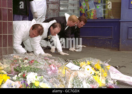 POLICE FORENSIC EXPERTS MAKE A FINGERTIP SEARCH OF THE SCENE MARKED BY FLOWERS AT THE SCENE OF THE BOMB BLAST IN WARRINGTON. Stock Photo