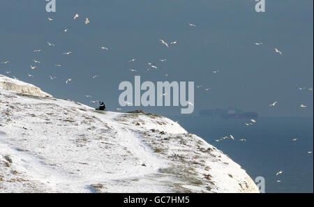 A couple enjoy a stroll along the top of the White Cliffs in Dover, Kent, as the cold weather continues. Stock Photo