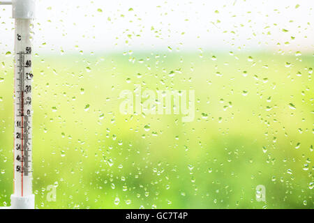 green background - raindrops on window pane and thermometer in summer day Stock Photo