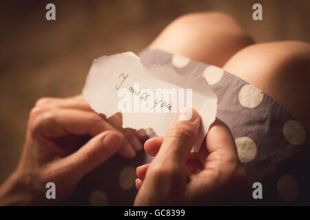 Top view of woman in dotted dress holding a paper message with the text I miss you Stock Photo