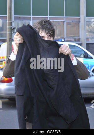Singer Pete Doherty tries to shield his face from the waiting media as he arrives at Gloucester Crown Court where he is accused of dangerous driving after a gig. Stock Photo
