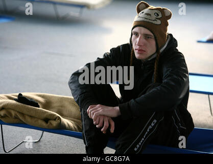 Tom, who is homeless, sits on a bed at one of nine temporary centres across London set up by the homeless charity Crisis, at Ivax Quays, Royal Docks, in east London. Stock Photo