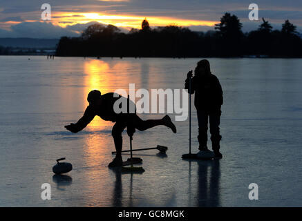 A Curler from the Port of Menteith Curling Club throws a stone on the Lake of Menteith during a curling match. Stock Photo