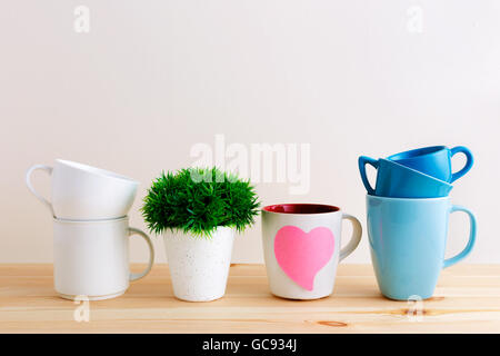 Mug and cup stack and white cups on wood kitchen table Stock Photo