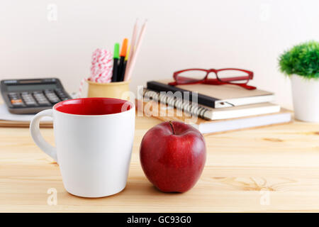 White coffee mug mockup with red apple on wooden table Stock Photo