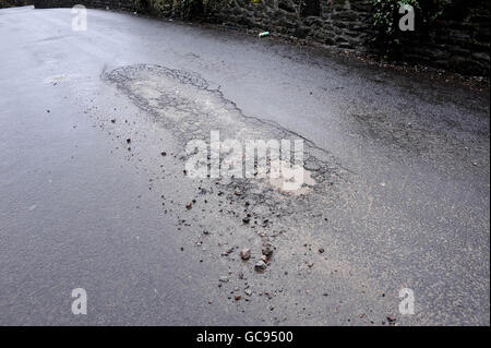 A pothole begins to form with a series of cracks and loose debris after the big freeze in the UK.