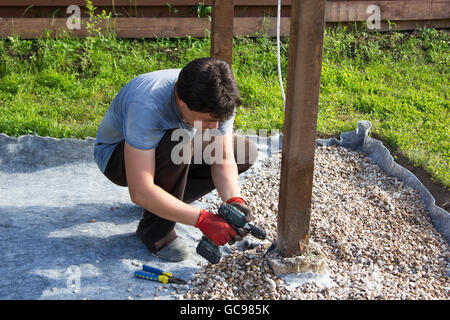 man fixes an electrical cord on a wooden post Stock Photo