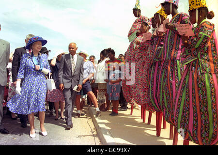 Queen Elizabeth II smiles at welcome messages displayed by colourful stilt walkers during her visit to Anguilla. Stock Photo