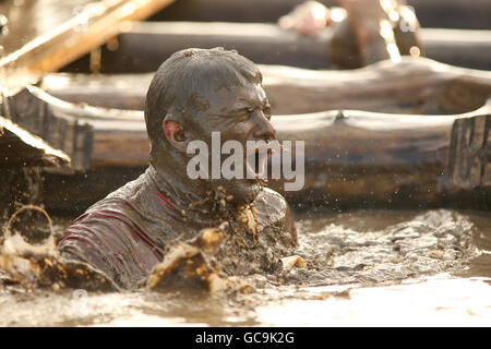 A competitor emerges from the water tunnel during tough guy Stock Photo