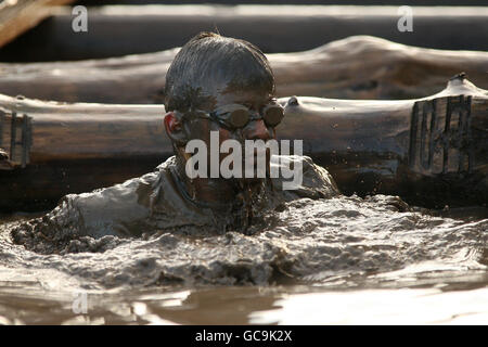 A competitor emerges from the water tunnel during tough guy Stock Photo