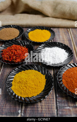 Spices in black ceramic plates on wooden background. Various spices selection. Six plates with different colorful spices Stock Photo