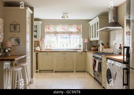 Country style kitchen with units from Neptune and tumbled limestone floor tiles. The Roman blind is made up in Kate Forma's Rose Stock Photo
