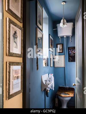 Framed artwork in blue washroom with wall-mounted cistern in Nottinghill home, London, UK Stock Photo