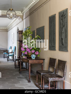 Pale grey octagonal stone floor in hall with old Fornasetti lead printing plates on the wall Stock Photo