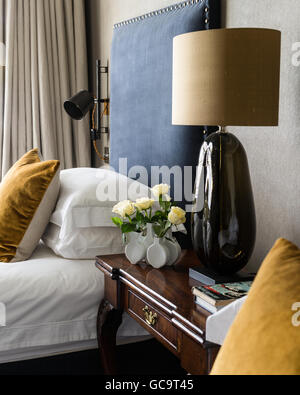 A Port Romana lamp in between twin beds with headboards covered in Turnell & Gignon's Decortex Fizzy Stock Photo