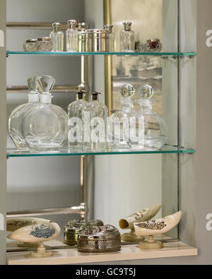 Assorted glass bottles on mirrored bathroom shelf Stock Photo