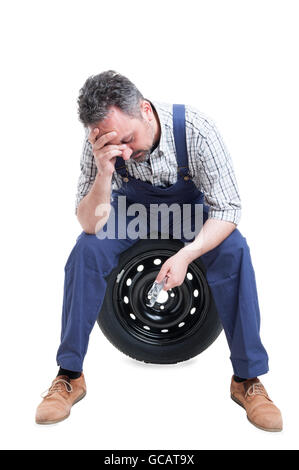 Stressful job concept with exhausted mechanic in overallas holding steel wrench isolated on white Stock Photo