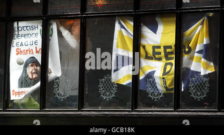 A man puts up a SDL poster in the window of Jenny Ha's bar on the Royal Mile, Edinburgh. Anti-fascist protesters targeted what they said was a gathering of the far-right Scottish Defence League (SDL). Protesters said members of the SDL were inside Jenny Ha's bar and vowed to stay in the area until they left the city. Stock Photo