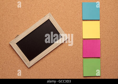 blackboard with wooden frame and four colored notes on cork background Stock Photo