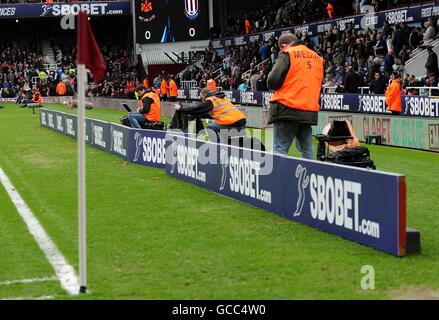Temporary advertising boards which have been placed close to the side of the pitch, to prevent players taking a long run up when taking a throw in. Stock Photo