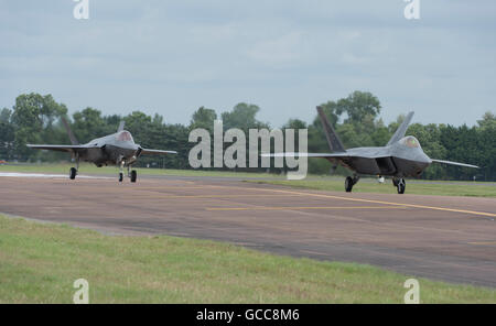 RAF Fairford, Gloucestershire. 8th July, 2016. Day 1 of the Royal International Air Tattoo (RIAT) with international military aircraft on display from around the world. Two 5th generation stealth aircraft, the Lockheed Martin F-35 Lightning II (left) and F-22 Raptor on the taxiway. Credit:  aviationimages/Alamy Live News. Stock Photo