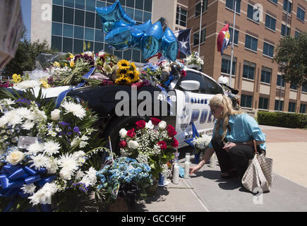 Dallas, Texas, USA. 8th July, 2016. NAKIA MARTINEZ places a candle next to a Dallas police car set up as a temporary memorial for 5 slain officers in front of the Dallas Police Department Headquarters. A sniper killed four Dallas police officers and one Dallas Area Rapid Transit officer during a protest by Black Lives Matter. Credit:  ZUMA Press, Inc./Alamy Live News Stock Photo