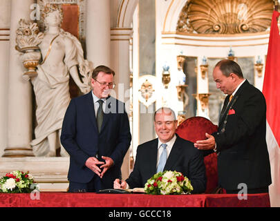 Gotha, Germany. 9th July, 2016. Albert II (m), Prince of Monaco, writes his name into the 'golden book' at the festival hall of Friedenstein Castle in Gotha, Germany, 9 July 2016. Beside him stand the governor of Thuringia, Bodo Ramelow (l, Die Linke) and mayor of the city of Gotha, Knut Kreuch (SPD). The Prince is on a one-day visit to the former royal seat. Photo: Jens Kalaene/dpa/Alamy Live News Stock Photo