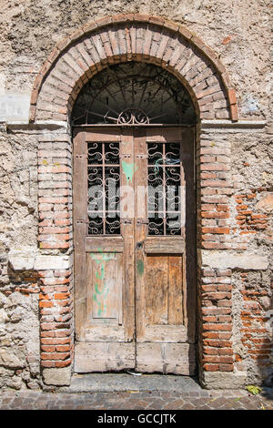 Old wooden door with upper railing and brick archway. Stock Photo