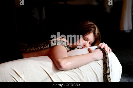 Chessington World of Adventures employee Carly Shutes enjoys a snake massage with a python, during the launch of the theme park's new area, Wild Asia. Stock Photo