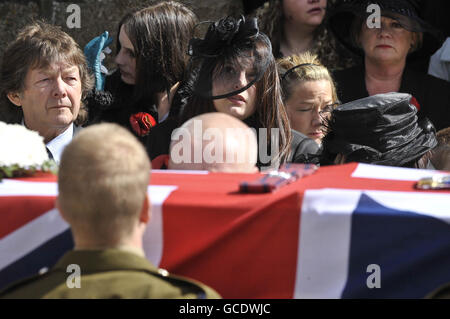 Charlotte Fox (centre), widow of Sergeant Paul Fox from 28 Engineer Regiment, attached to the Brigade Reconnaissance Force, stands with Paul's father Maurice Fox (left) behind the flag draped coffin at his funeral service at St Ia's Church, St Ives, Cornwall. Stock Photo