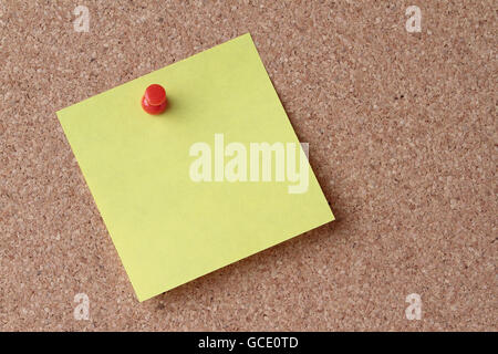 yellow note on a cork board with a red push pin Stock Photo