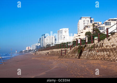 Concrete retaining wall  on early morning beach front against commercial and residential complexes in Umhlanga Rocks Stock Photo