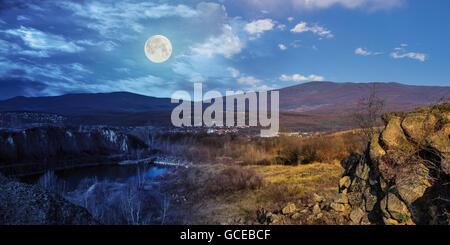 day and night collage of small lake in an abandoned stone quarry in the mountains outside the city with full moon Stock Photo