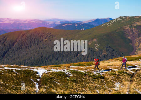 Two Hikers walking along Mountain ridge with Sun shining Stock Photo