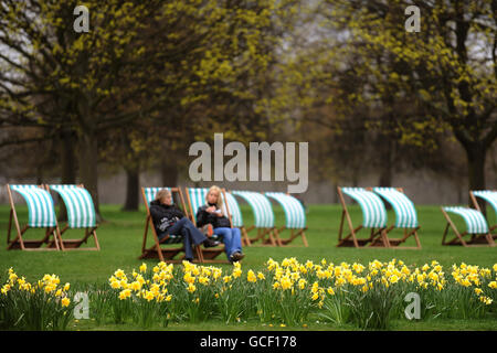 Two girls sit in deckchairs in the spring weather in London's Hyde Park. Stock Photo