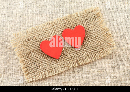 Two red painted wooden hearts on raw light gay linen cloth Stock Photo