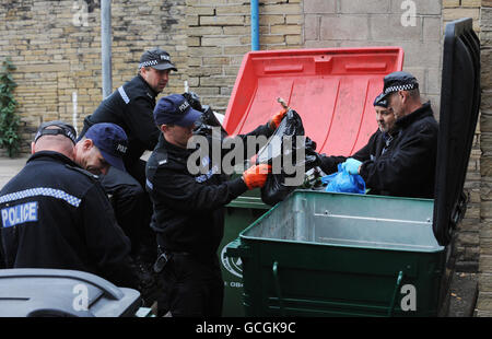 Police officers search through rubbish bins in the area around the red light district of Bradford following the discovery of body parts in the River Aire, in Shipley, West Yorkshire. Stock Photo