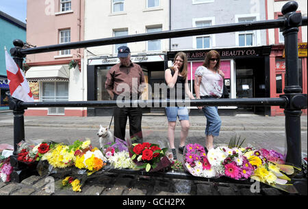 People look at floral tributes that have been left close to the scene where taxi driver Darren Rewcastle was shot in Whitehaven, Cumbria. Stock Photo