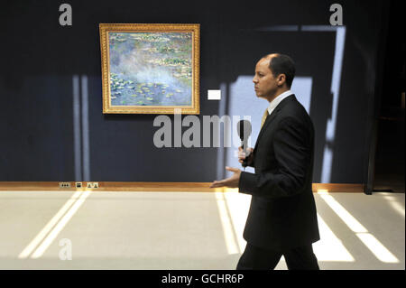 A TV presenter walks past Claude Monet's Nympheas, valued at 30 million to 40 million at Christie's in London, part of their Masterpieces Through The Ages exhibition which is open to the public until Thursday and features some of the highlights of the summer auction season. Stock Photo