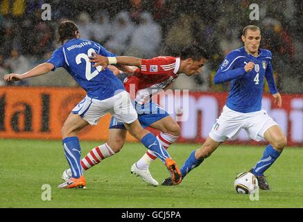 Italy's Riccardo Montolivo (left) and Giorgio Chiellini (right) in action against Paraguay's Lucas Barrios (centre) Stock Photo