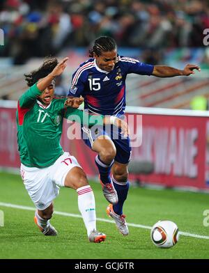 Soccer - 2010 FIFA World Cup South Africa - Group A - France v Mexico - Peter Mokaba Stadium. Mexico's Dos Santos Giovani (left) falls to the floor after battling France's Florent Malouda (right) for the ball. Stock Photo