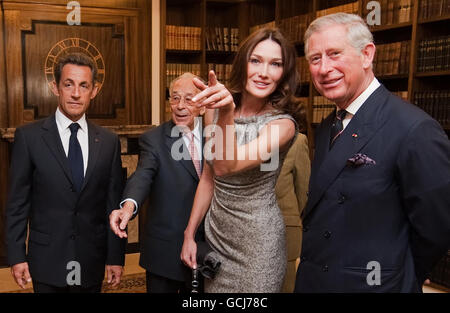 French President Nicolas Sarkozy (left), his wife Carla Bruni-Sarkozy (2nd right) and Britain's Prince Charles (right), look at photographs of French President Charles De Gaulle during a visit to the former headquarters of the Free French, at Carlton Gardens in central London. Stock Photo