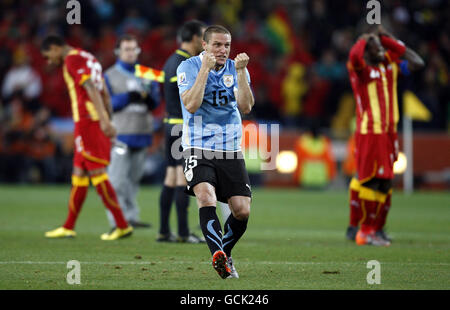 Soccer - 2010 FIFA World Cup South Africa - Quarter Final - Uruguay v Ghana - Soccer City Stadium. Uruguay's Diego Perez (centre) celebrate winning the penalty shootout as Ghana players stand around dejected Stock Photo