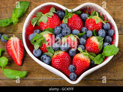 Fresh berries in heart shaped bowl. Healthy food concept. Top view Stock Photo