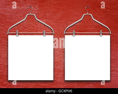 Close-up of two square blank frames hanged by clothes hanger against red rough concrete wall background Stock Photo