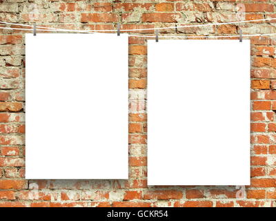 Close-up of two blank frames hanged by pegs against orange weathered brick wall background Stock Photo