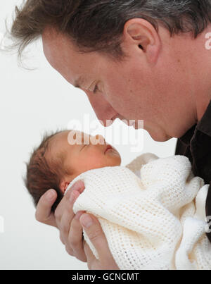 Prime Minister David Cameron holds his baby daughter, Florence Rose Endellion Cameron who was born on Tuesday August 24, during their summer holiday in Cornwall. Stock Photo